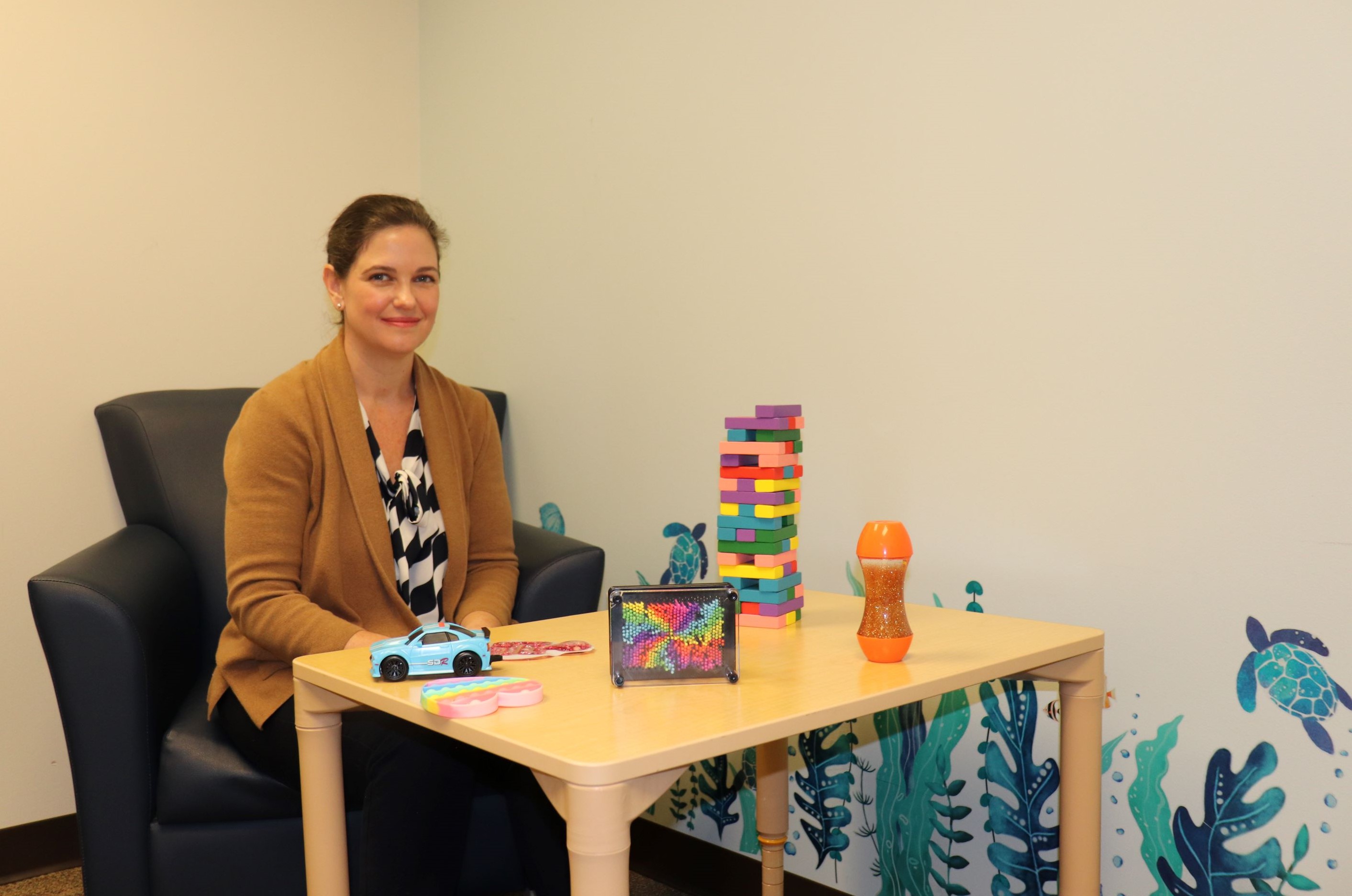 Alex Bey sitting in a pediatric exam room with colorful toys