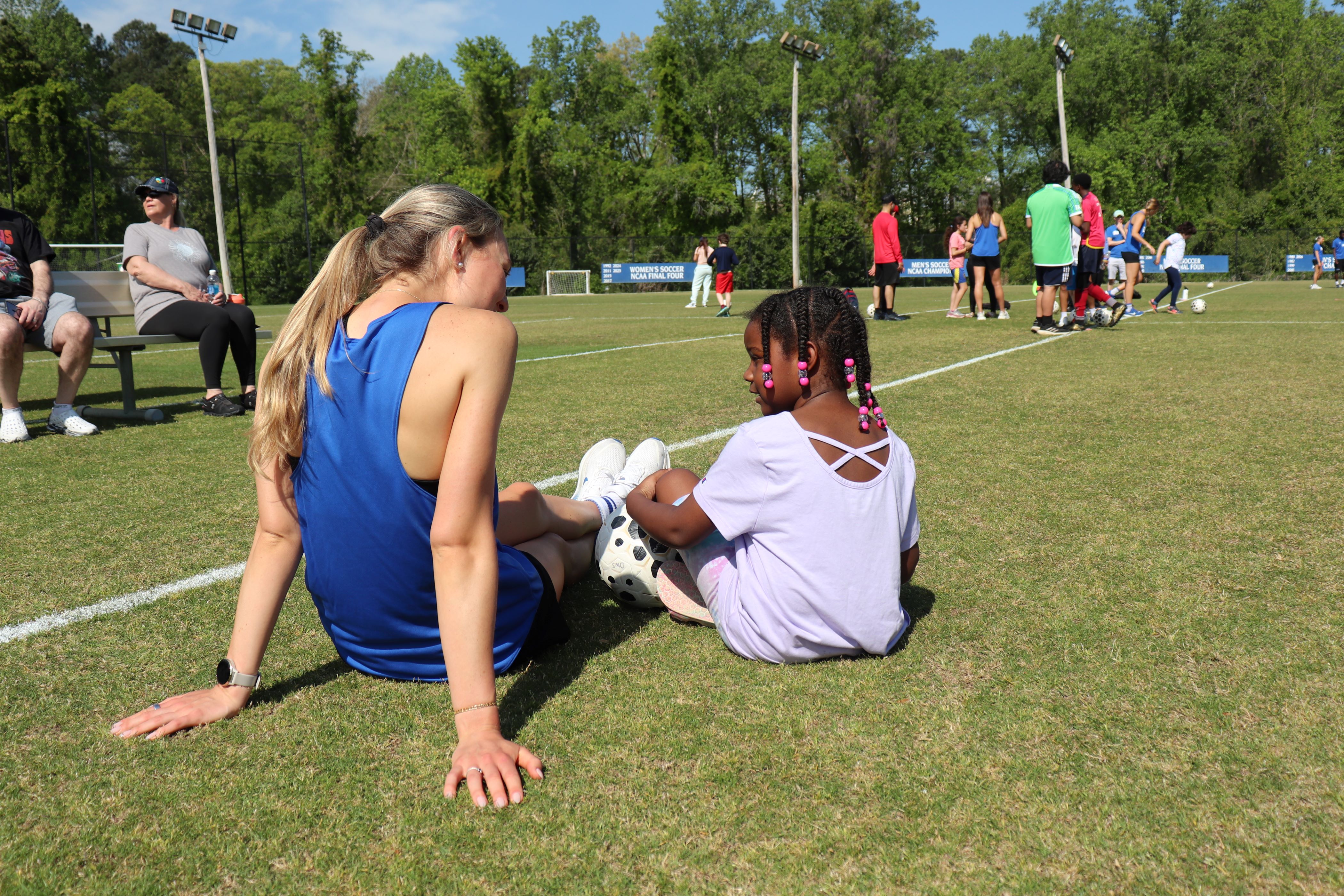 Duke women's soccer player sits with a young girl