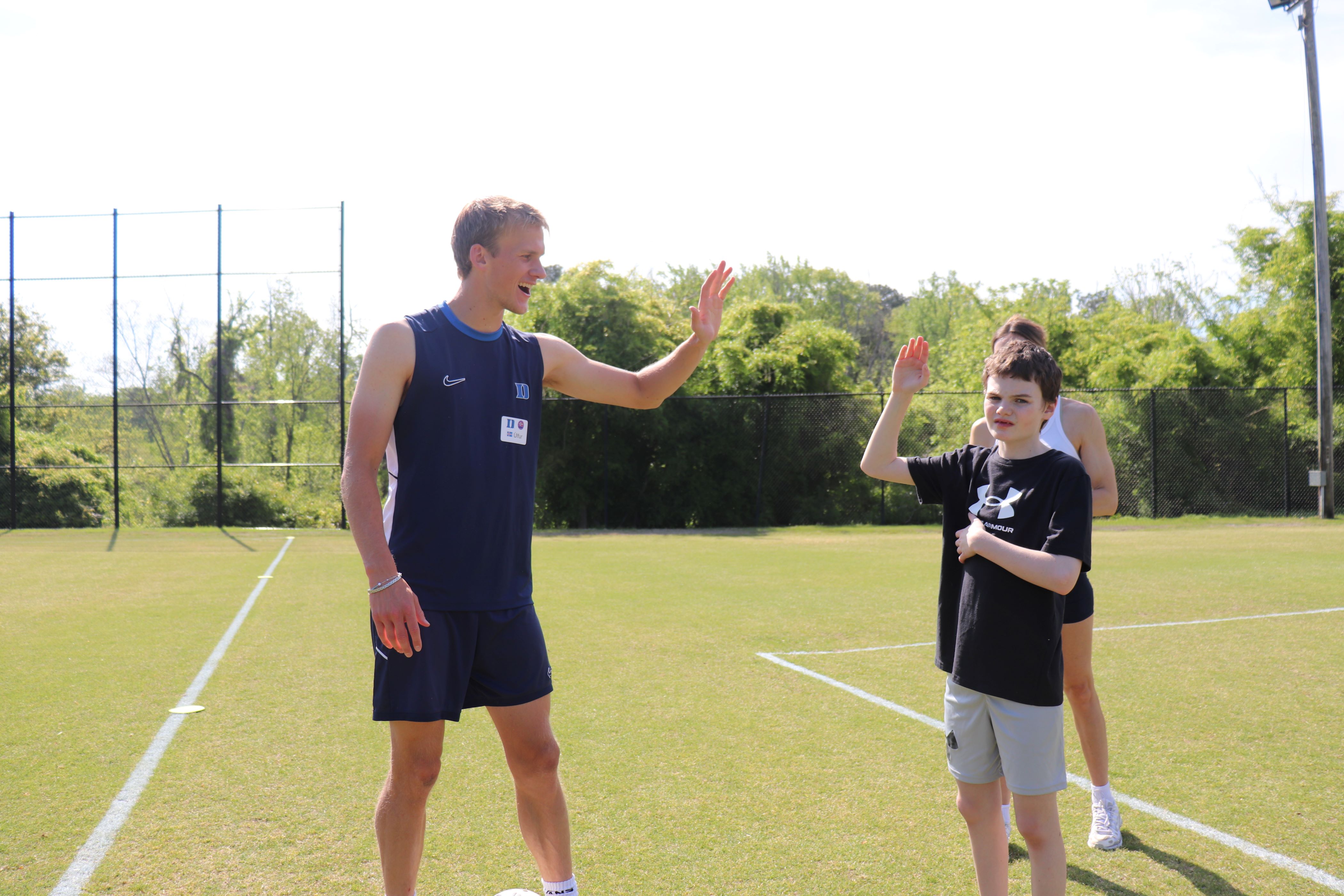 Duke soccer player Ulfer gives a high-five to a boy
