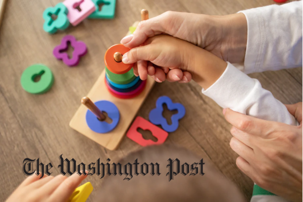 hands of a child and adult holding a ring toy together