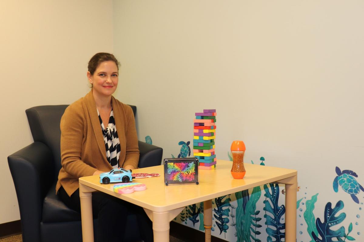 Alex Bey sitting in a pediatric exam room with colorful toys