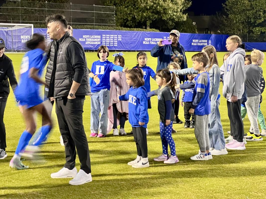 Duke womens soccer players greet kids on the field