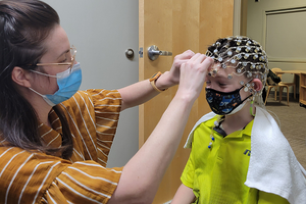 Researcher places EEG hat on child