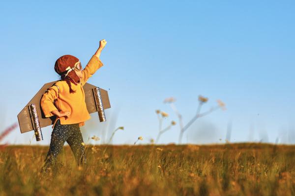 Child in cape pretending to take off like rocket