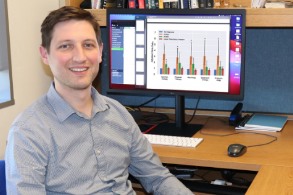 man researcher at desk with data showing on his computer