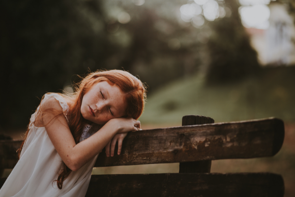 sad sleepy child on park bench