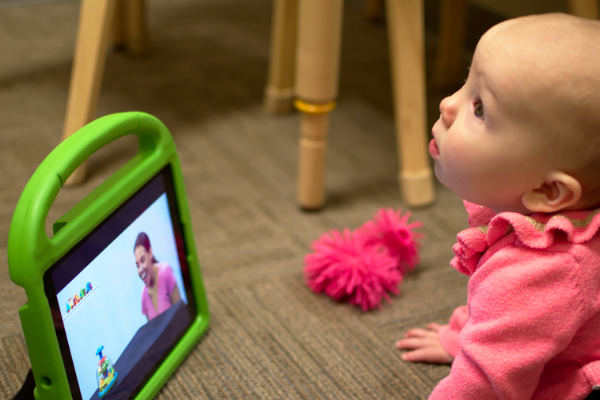 Baby on floor with iPad watching movies from autism screening app