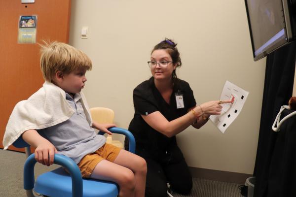 Samantha Major looking at a child and pointing to instructions on a piece of paper
