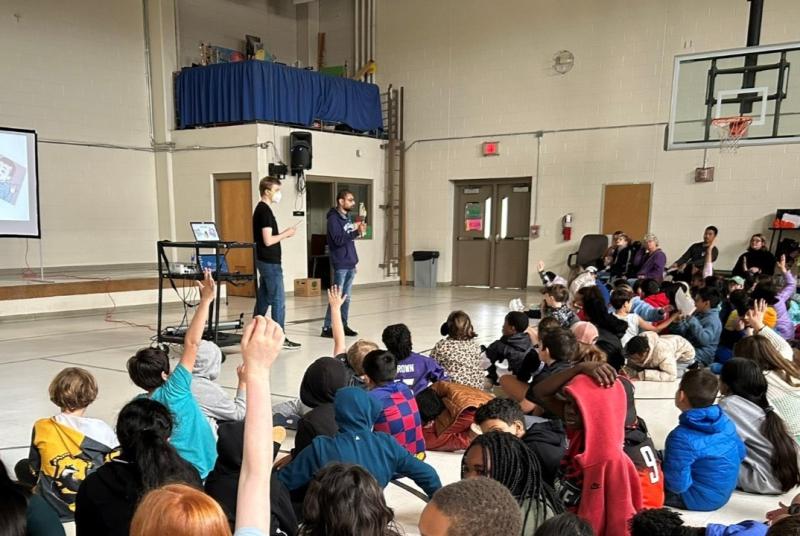 children raise their hands during a presentation by Sam Brandsen and Raghav Swaminathan