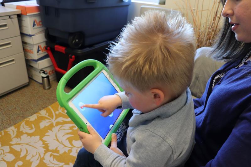 A child points at the screen of a tablet