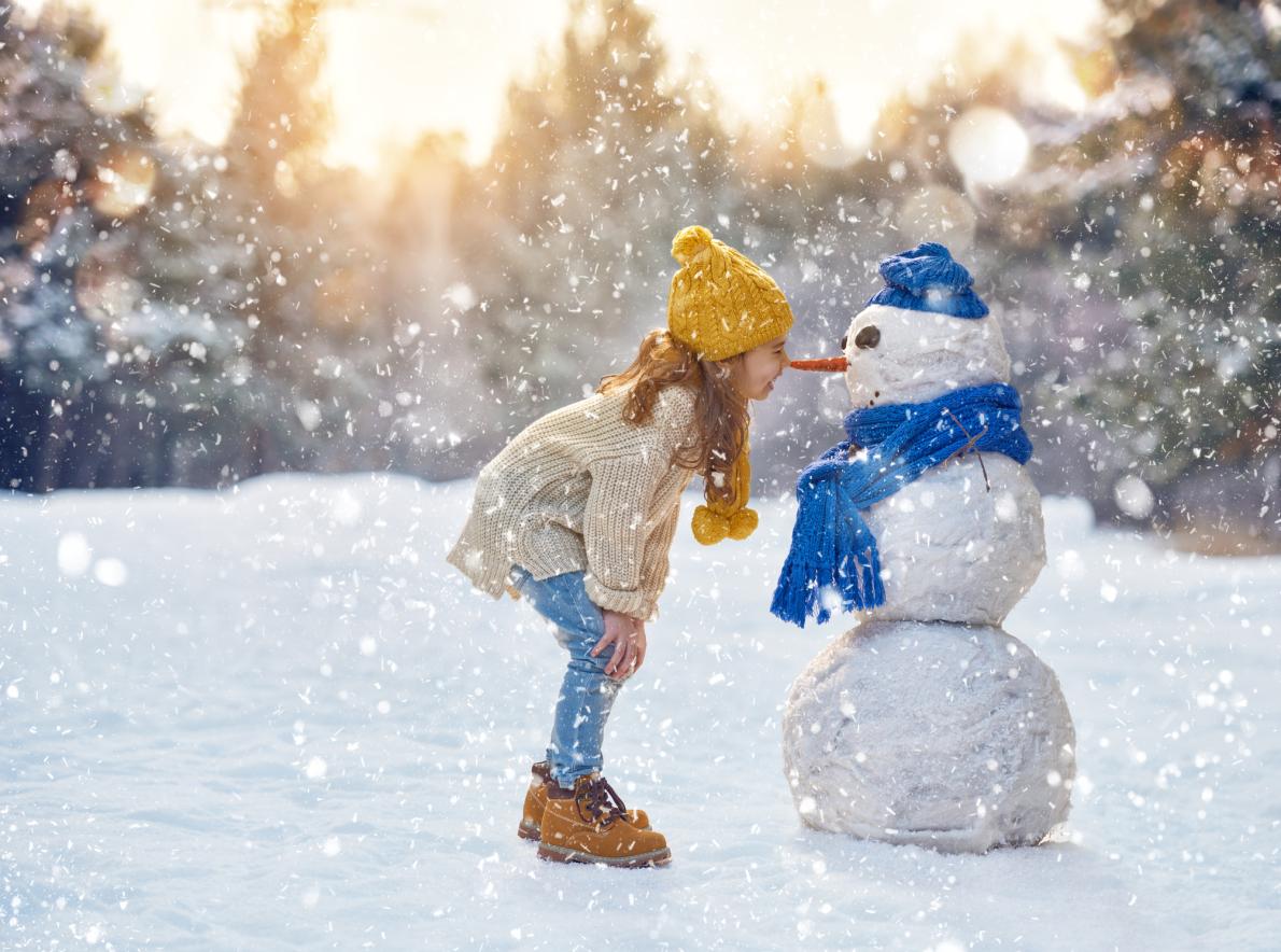 A girl looks at a snowman