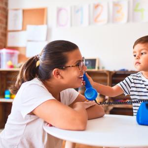 A childing holding a toy phone to an adult's ear.