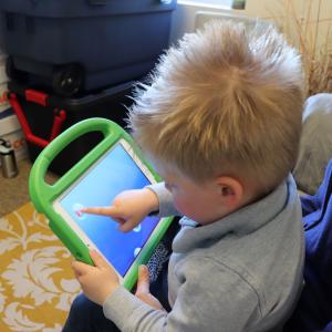 A child points at the screen of a tablet